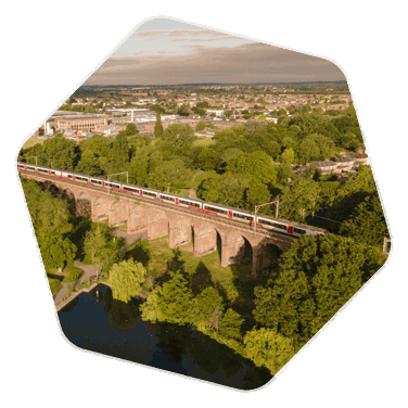 An aerial shot of the Chelmsford viaduct which spans over a park, there is a train travelling over the viadcut.