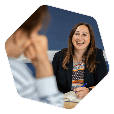 Helen Quinnell, Economic Development Officer, smiling at another person out of shot whilst holding a pen that is poised to write in the notepad in front of her