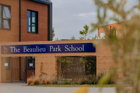 The Beaulieu Park School building with gates and a tree in the foreground