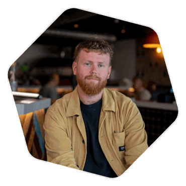 Headshot of the owner of Moto Pizza, a bearded younger man